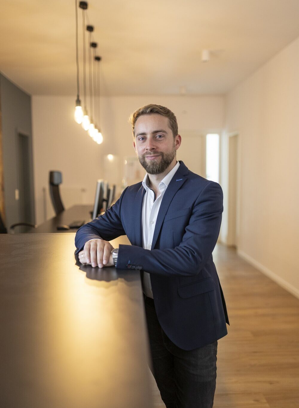 Business-Porträt: Mann im Sakko lehnt entspannt an einer Theke