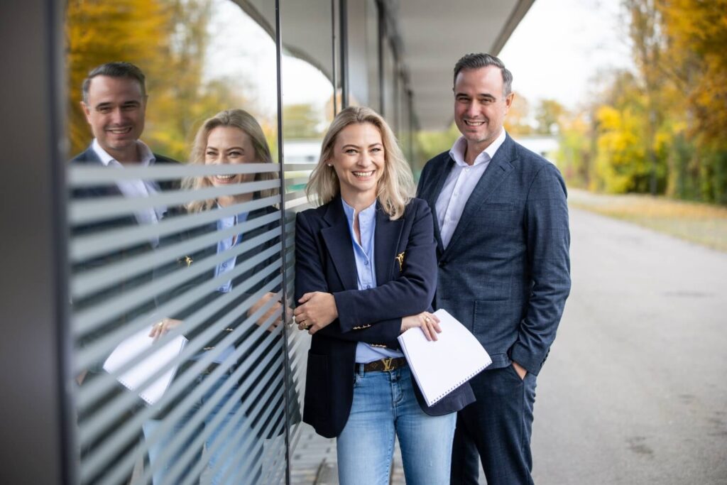 Teamfoto: vier Menschen vor einem Bürogebäude im Herbst