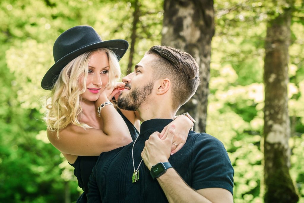 Frau mit Hut lehnt sich lachend an ihren Partner