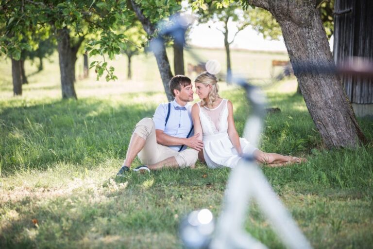 Paar sitzt im Gras unter Obstbäumen