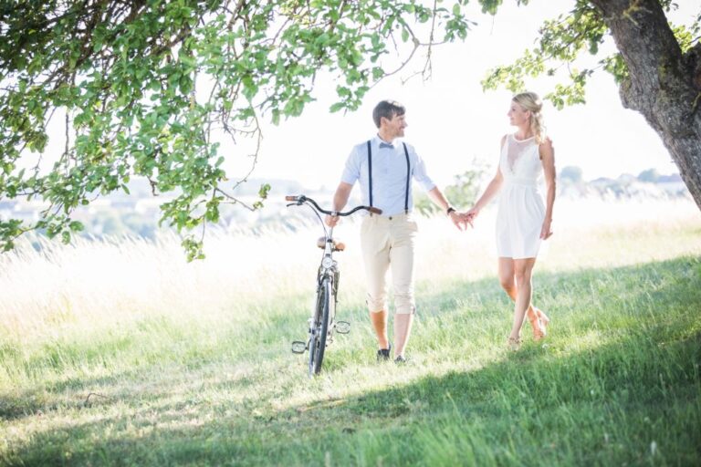 Paar spaziert mit Fahrrad über eine Streuobstwiese