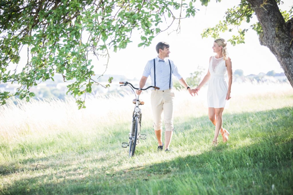 Paar spaziert mit Fahrrad über eine Streuobstwiese